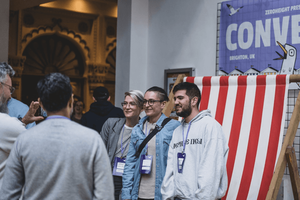 Side-angle of three attendees posing for a photo in the Converge 2024 reception area.